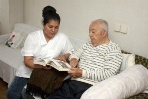 a nurse reading to an elderly patient